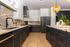 Luxurious kitchen with modern black cabinets, marble countertops, and elegant pendant lighting.