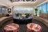 Elegant living room with modern furniture, featuring curved sofas, stylish cushions, and a large central coffee table. Abundant natural light streams through floor-to-ceiling windows, highlighting decorative plants and contemporary artwork for a luxurious ambiance.