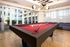 Elegant game room with a sleek red pool table and modern lighting, perfect for entertaining.