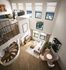 Chic loft apartment with a modern spiral staircase, bright open living space, and stylish decor, bathed in natural light from large windows.
