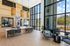 Elegant apartment lobby with high ceilings, featuring chic wicker pendant lighting, expansive windows, and modern furniture for a welcoming atmosphere.