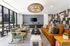 Chic and modern living room with large windows, stylish orange couch, elegant decor, and a unique geometric feature wall, perfect for relaxation and entertainment.