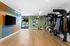 Modern fitness room featuring TRX equipment, a TV, and colorful accent walls, overlooking an exterior pool area through large windows.
