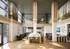 Elegant communal space featuring modern wood floors, luxurious marble countertops, and chic green seating, with high ceilings and abundant natural light.