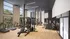 Bright and modern fitness center featuring treadmills, strength training machines, and ample space with floor-to-ceiling windows.
