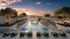 Luxurious rooftop pool with chic sun loungers and elegant decor, set against a stunning sunset mountain view.