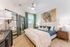 Elegant bedroom with modern decor, featuring a plush bed, stylish wall art, and floor-length mirrors reflecting natural light.