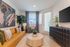 Inviting living room with modern decor, featuring a stylish tan sofa, abstract art, lush greenery, and natural light.