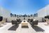 Chic rooftop terrace featuring modern outdoor seating and a central fire pit, offering stunning views in a serene urban setting.