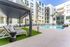 Luxurious apartment courtyard featuring a sparkling pool, sun loungers, and modern architecture.