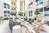 Chic apartment courtyard with modern seating, vibrant pillows, lush greenery, and string lights creating a welcoming outdoor space.
