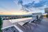 Stunning rooftop pool with panoramic city views and elegant lounge chairs at sunset, offering a luxurious urban oasis.