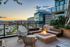 Chic urban balcony with cozy seating and a stylish fire pit overlooking a stunning cityscape at sunset.