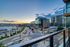 Panoramic urban view from a modern apartment balcony showcasing vibrant city lights, upscale buildings, and a stunning sunset backdrop.