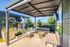 Chic outdoor lounge with modern seating under a stylish pergola, featuring lush greenery and a mounted TV for ultimate relaxation.