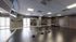 Modern fitness studio with sleek wood flooring, large mirrors, yoga mats, exercise balls, and TRX equipment, ideal for dynamic workouts.