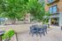 Inviting outdoor terrace featuring lush greenery, cozy seating area, and modern building backdrop for a tranquil city retreat.