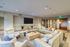 Contemporary living room with elegant seating, plush pillows, and a sleek wall-mounted TV, creating a cozy and upscale ambiance.
