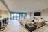 Luxurious modern living room with plush seating, sleek decor, and expansive glass doors opening to a scenic outdoor patio.