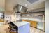 Modern kitchen with sleek countertops, high-end stovetop, stylish bar seating, and elegant shelving.