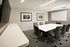 Modern conference room with sleek white table, executive chairs, and minimalistic wall art.