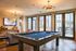 Modern communal lounge featuring a pool table, cozy seating, and large windows overlooking a stylish patio.