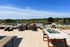 Luxurious rooftop terrace featuring chic outdoor seating, a foosball table, and breathtaking views of lush green surroundings and blue skies.