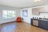 Bright apartment with stylish wood flooring, modern kitchen amenities, and vibrant natural light from large windows.