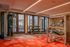 Modern apartment gym with state-of-the-art equipment, vibrant red flooring, and large windows for natural light.