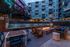 Elegantly designed outdoor area featuring a modern fire pit surrounded by cozy seating, overlooking a chic apartment complex with vibrant murals.