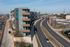 Modern apartment building with sleek design along a bustling urban road, showcasing stylish balconies and vibrant city living.