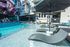 Chic apartment pool area boasting stylish sun loungers with umbrellas, vibrant mural backdrop, and modern architecture.