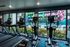 Modern gym with large windows overlooking a vibrant mural and poolside area, featuring state-of-the-art exercise equipment and treadmills.