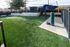 Charming outdoor space with lush green artificial turf, modern fencing, and shaded seating area for relaxation.