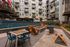 Modern apartment courtyard featuring vibrant mural, cozy fire pit surrounded by wooden chairs, and inviting outdoor seating area.