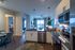 Modern open-concept kitchen and living area with chic lighting, sleek stainless steel appliances, and large windows offering natural light.