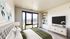 Elegant bedroom with plush bedding, modern decor, and a large window offering stunning city views.