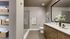 Modern bathroom with elegant design featuring a spacious walk-in shower, stylish wood cabinetry, large mirror, and chic decorative elements.