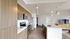 Modern open-concept kitchen with sleek wood cabinets, stainless steel appliances, and a spacious island overlooking a stylish living area.