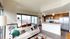 Modern apartment with an open-plan living space showcasing a chic kitchen, stylish seating area, and expansive city views through large windows.