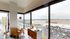 Bright apartment interior showcasing stunning panoramic city views through floor-to-ceiling windows, with cozy seating and a stylish sideboard.