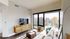 Bright, modern living room with city skyline views, featuring a sleek TV setup and stylish furnishings.