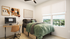 Modern bedroom with a large window view, featuring a cozy bed, stylish workspace, and vibrant decor accents.