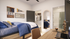Cozy bedroom with stylish decor, featuring a comfortable bed, closet, modern desk setup, and an elegant bathroom entrance.