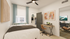 Charming bedroom with stylish decor, featuring a cozy bed, modern desk workspace, and closet with an inviting window view.