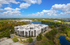 Luxurious apartment complex with a modern design, nestled in lush greenery by the tranquil lake, under a vibrant blue sky.