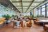 Chic communal lounge with stylish seating, vibrant greenery, and expansive windows offering city views.