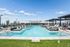 Luxurious rooftop pool with elegant lounge chairs and umbrellas, offering panoramic city views under a bright blue sky.