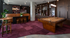 Chic recreation room with a stylish pool table, lounge seating, sports-themed decor, and rich wood shelving, perfect for entertainment.