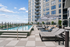 Luxury high-rise apartment building with an elegant rooftop pool, relaxing sun loungers, and stylish outdoor umbrellas, set against a vibrant cityscape.